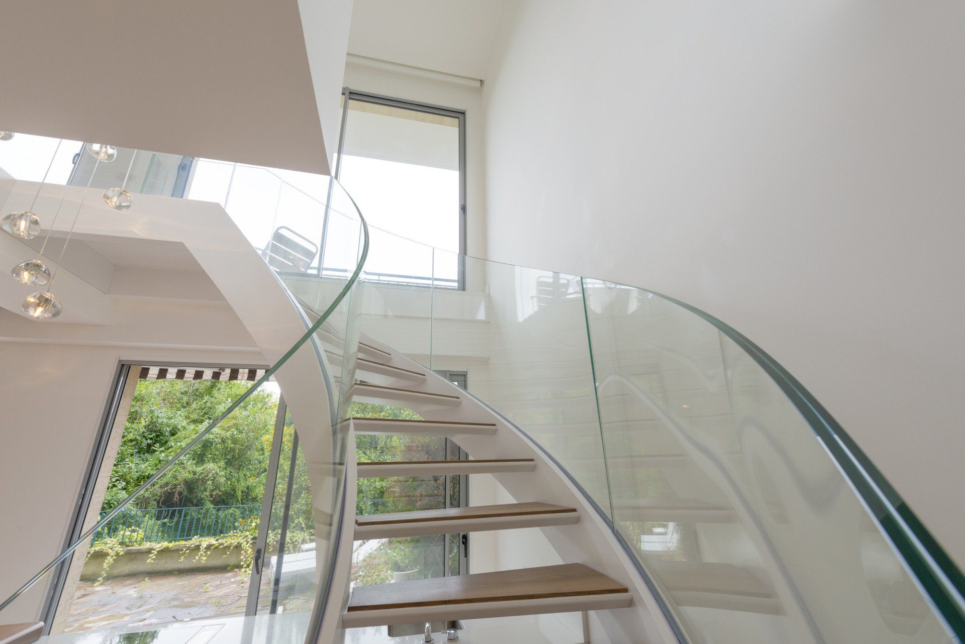 Curved staircase with glass balustrades and wooden steps in a modern home.