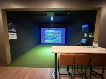 Golf instructor coaching student at indoor simulator