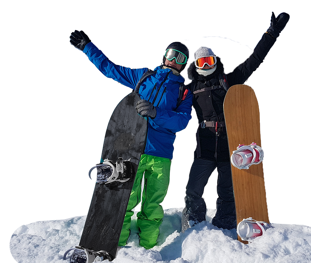 Two snowboarders standing on snow, holding boards and raising their arms on a mountain slope.