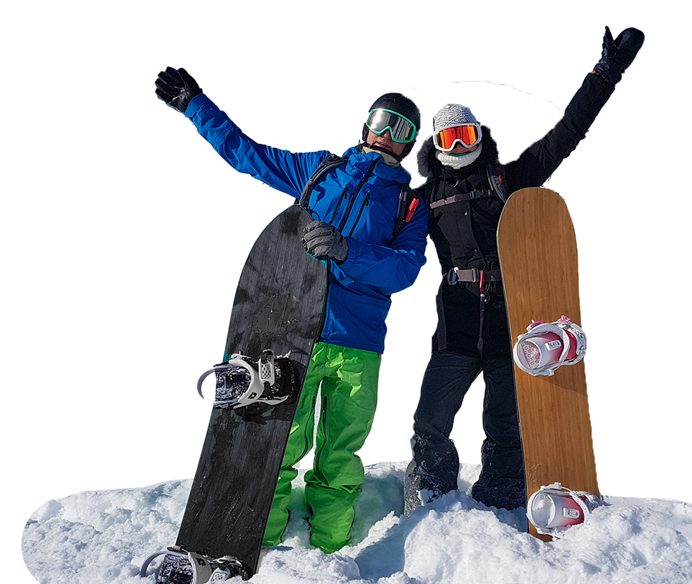 Two snowboarders standing on snow, holding boards and raising their arms on a mountain slope.
