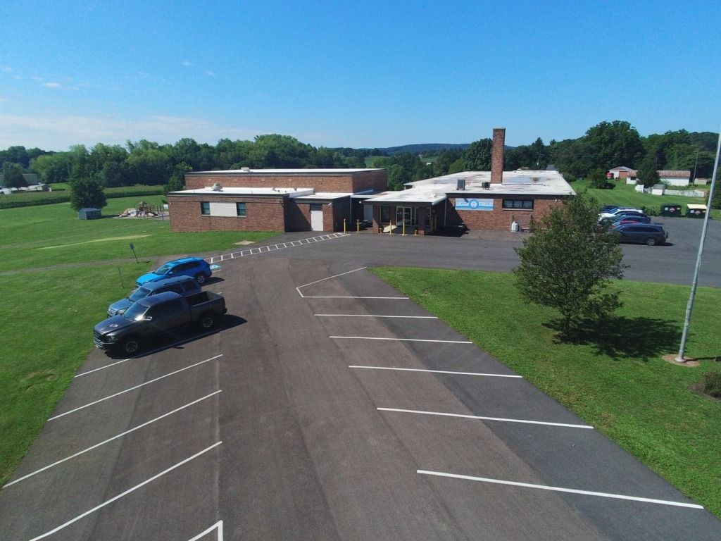 An aerial view of a parking lot with cars parked in front of a building.