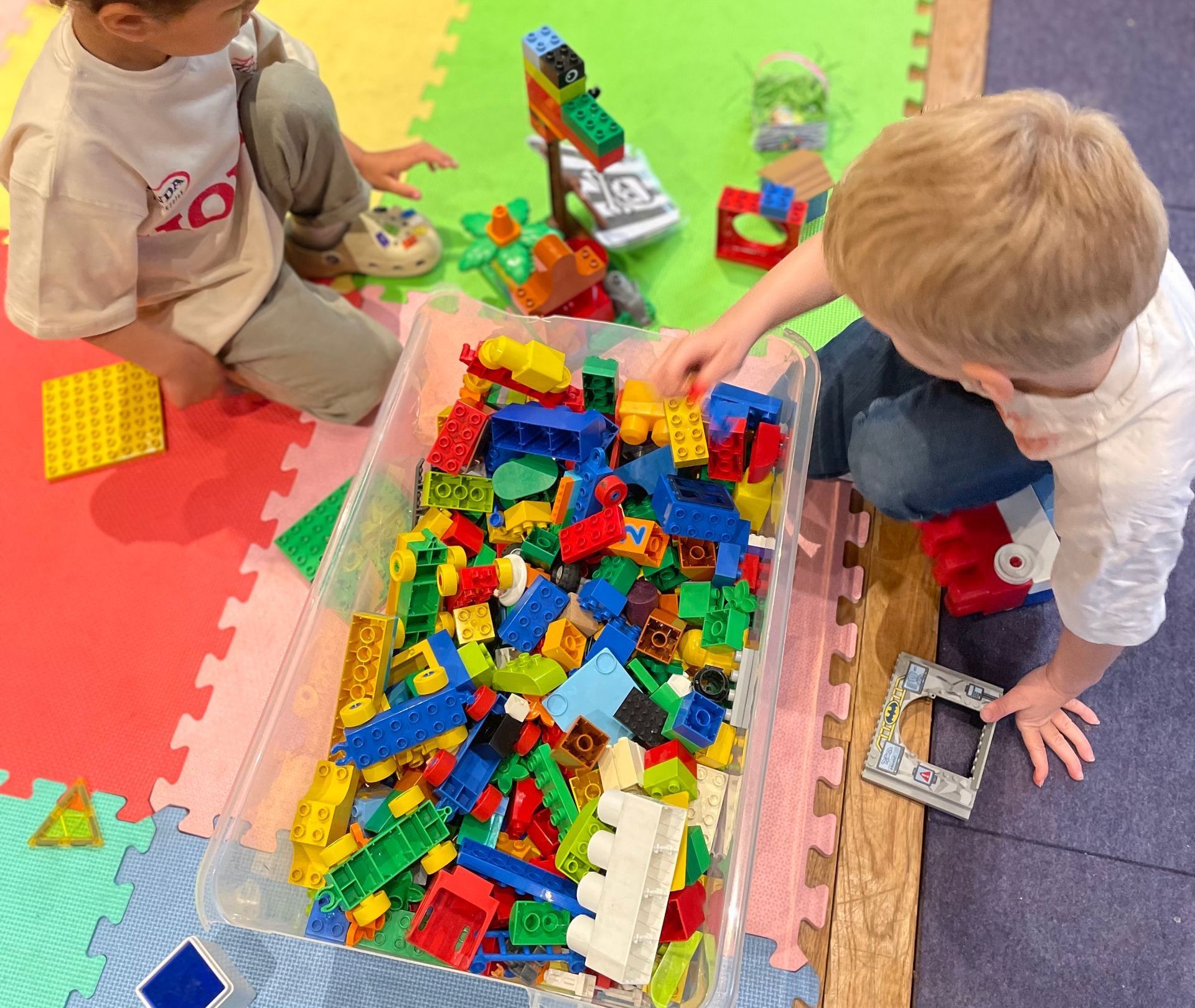 Two children playing with colorful building blocks in a room.