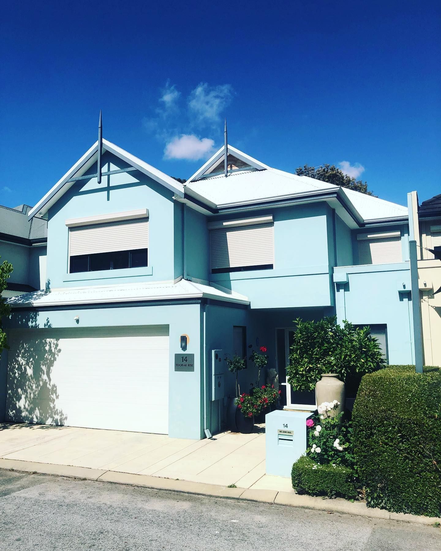 A blue house with a white garage door and a blue sky in the background