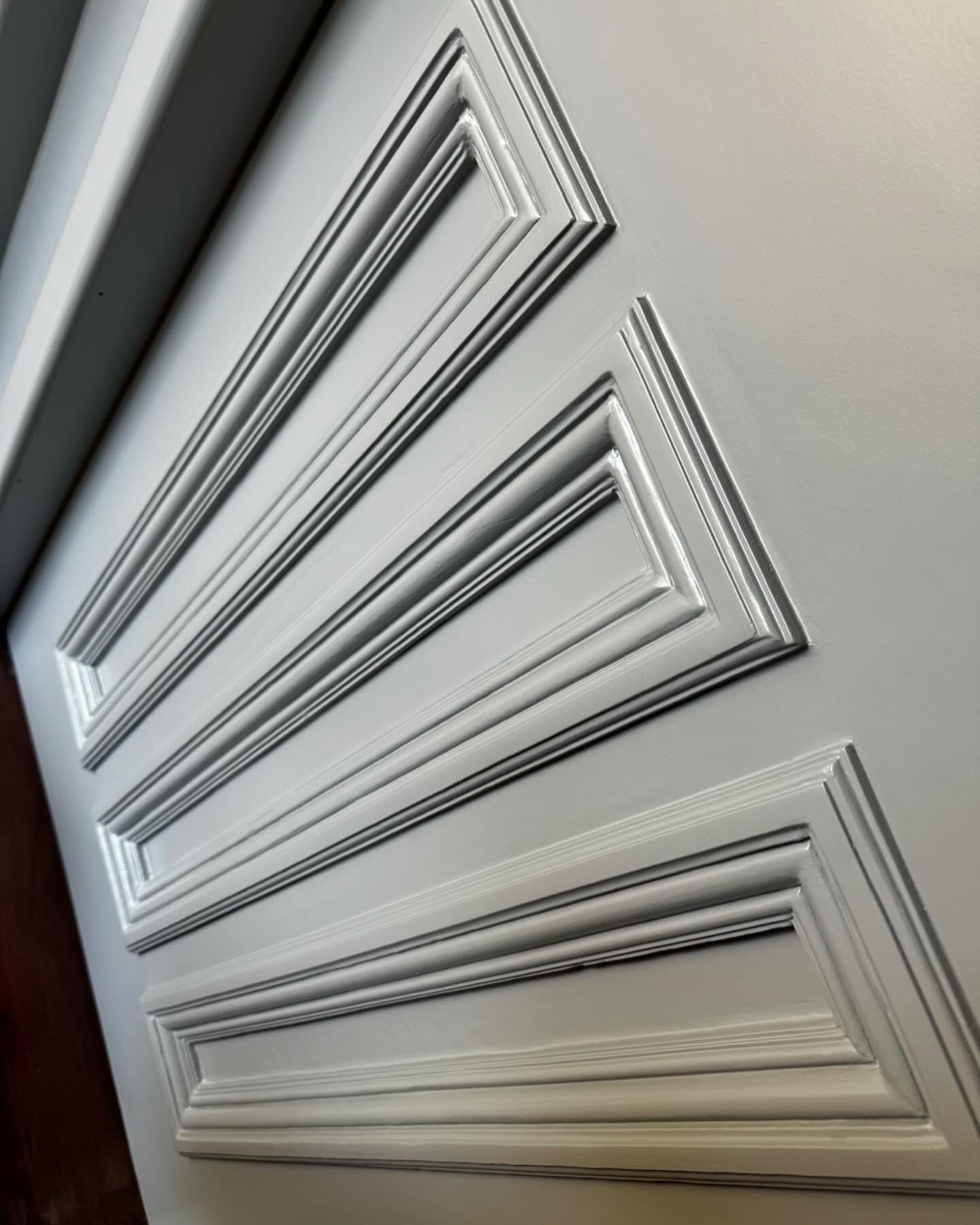 A close up of a white door with molding on it