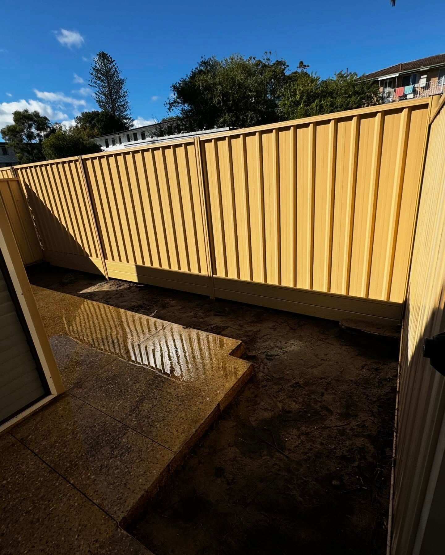 A yellow fence with a blue sky in the background