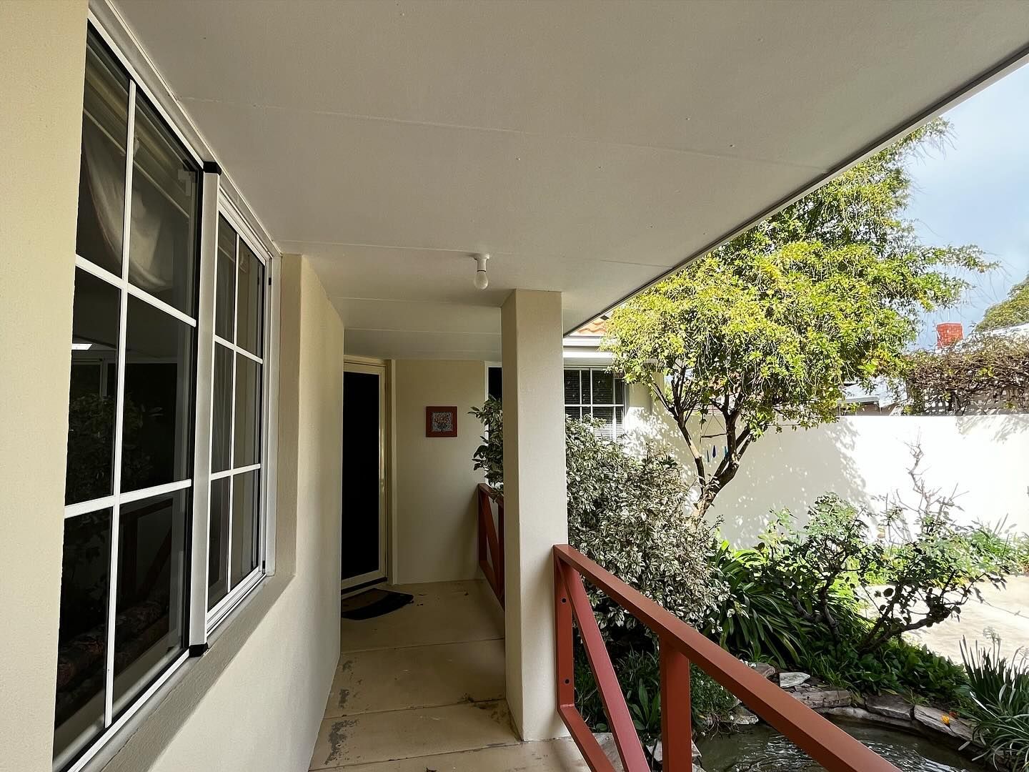 A hallway with a red railing and a window