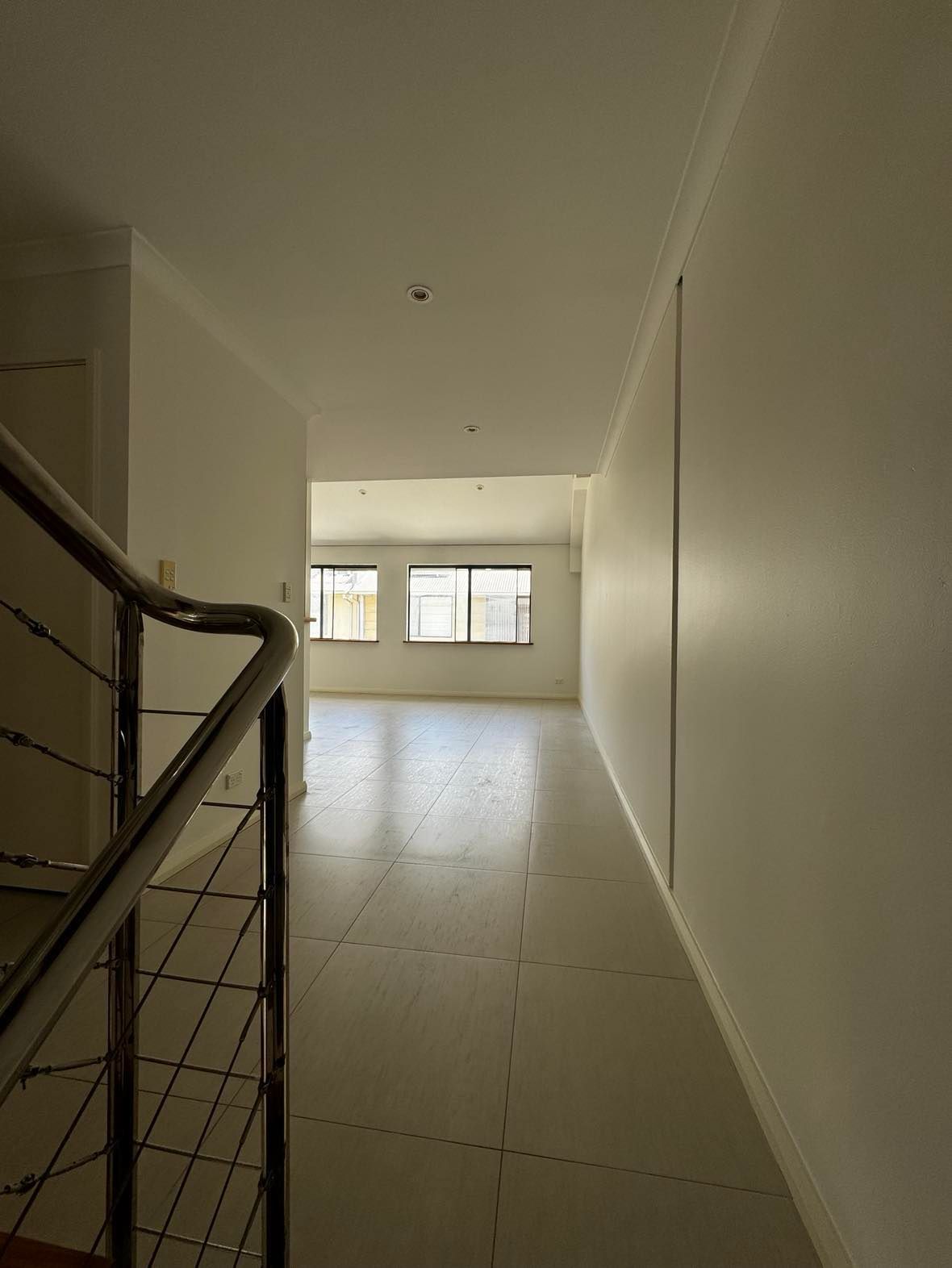 An empty hallway with stairs and a railing in a house