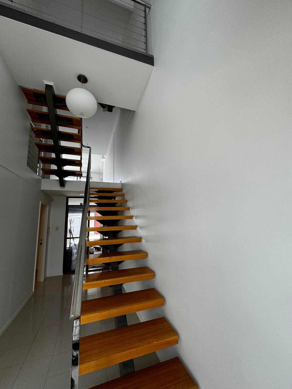A wooden staircase in a hallway with white walls