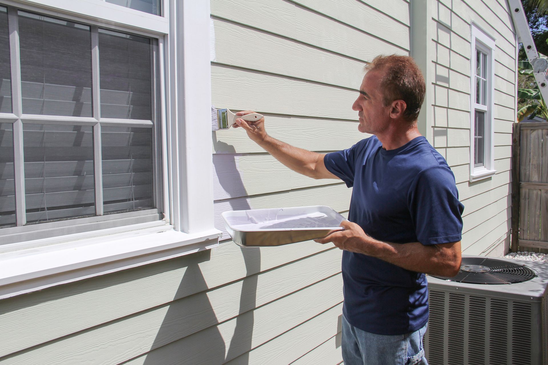 A man painting a house exterior, highlighting professional residential painters at work.