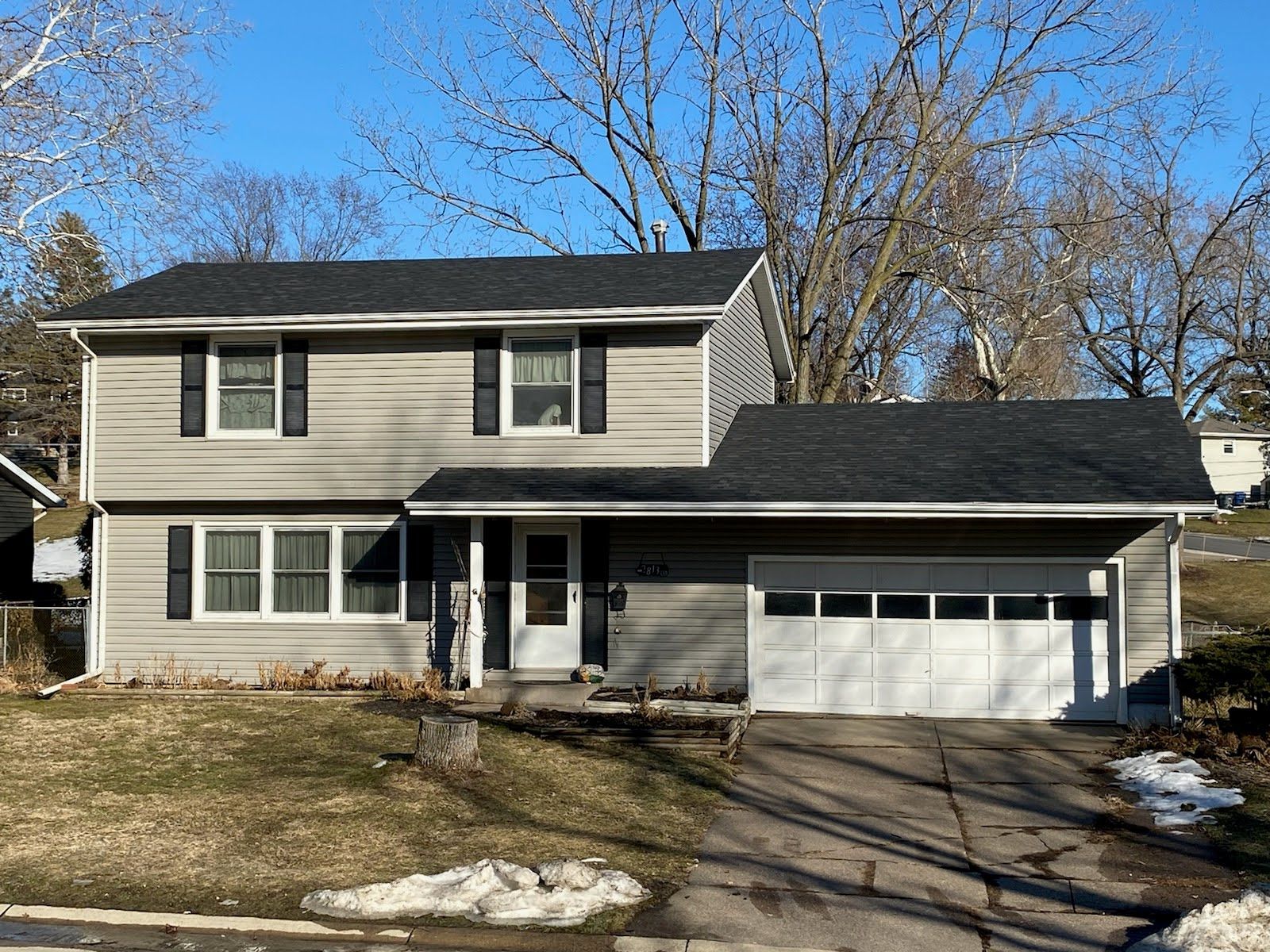 A large house with a black roof and a white garage door.