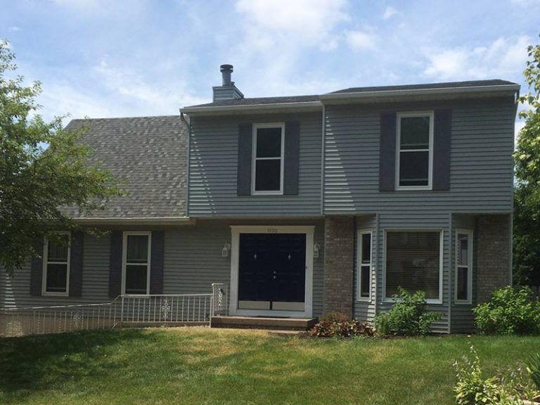 A large grey house with a blue door and shutters