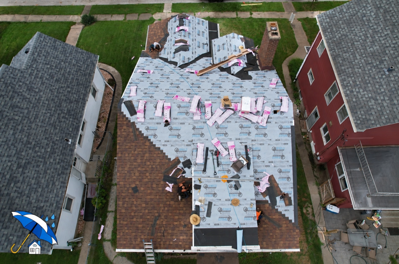 A person is holding a piece of asphalt shingles on a roof.