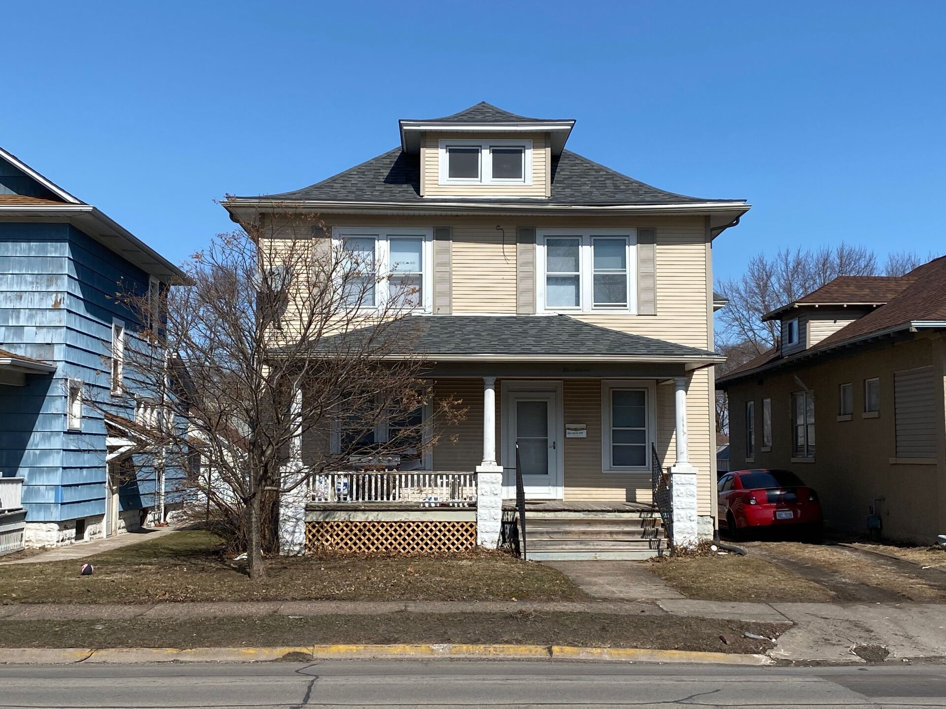 A house with a porch and a car parked in front of it