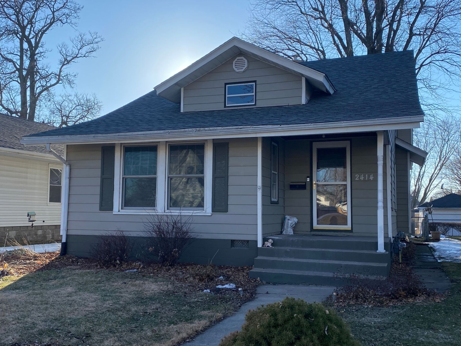 A small house with a porch and a blue roof.