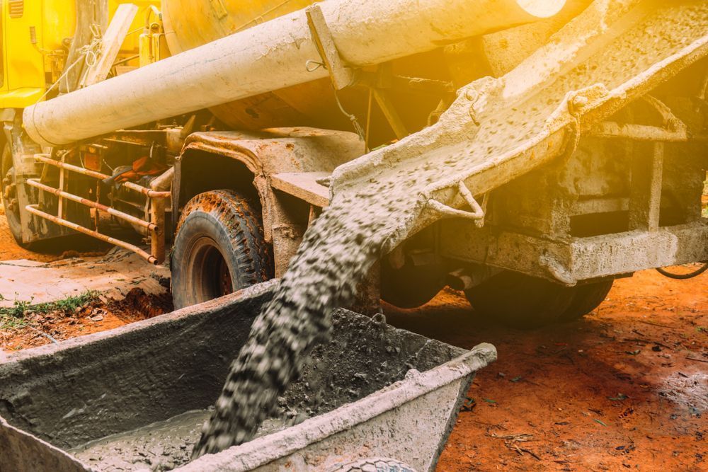 A Concrete Truck is Pouring Concrete Into a Bucket — Rowdraulics NQ Pty Ltd In Mount Louisa, QLD