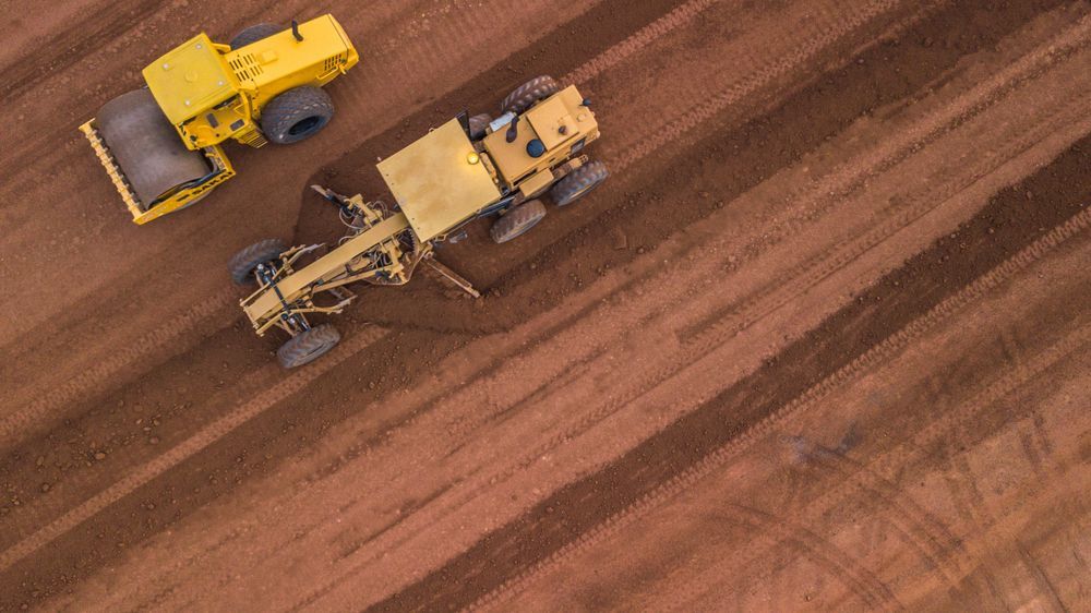 An Aerial View of Two Yellow Tractors Working on a Dirt Field — Rowdraulics NQ Pty Ltd In Mount Louisa, QLD