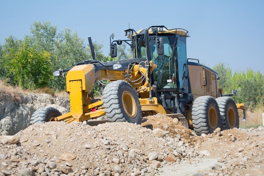 A Yellow Tractor is Driving Through a Pile of Rocks — Rowdraulics NQ Pty Ltd In Mount Louisa, QLD