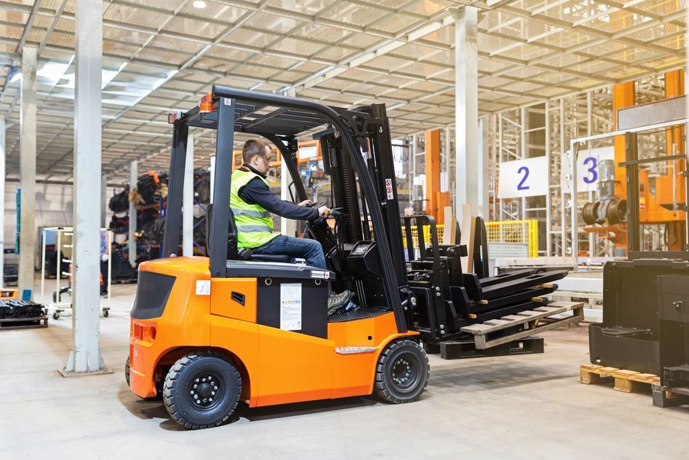 A Man is Driving a Forklift in a Warehouse — Rowdraulics NQ Pty Ltd in Mount Louisa, QLD