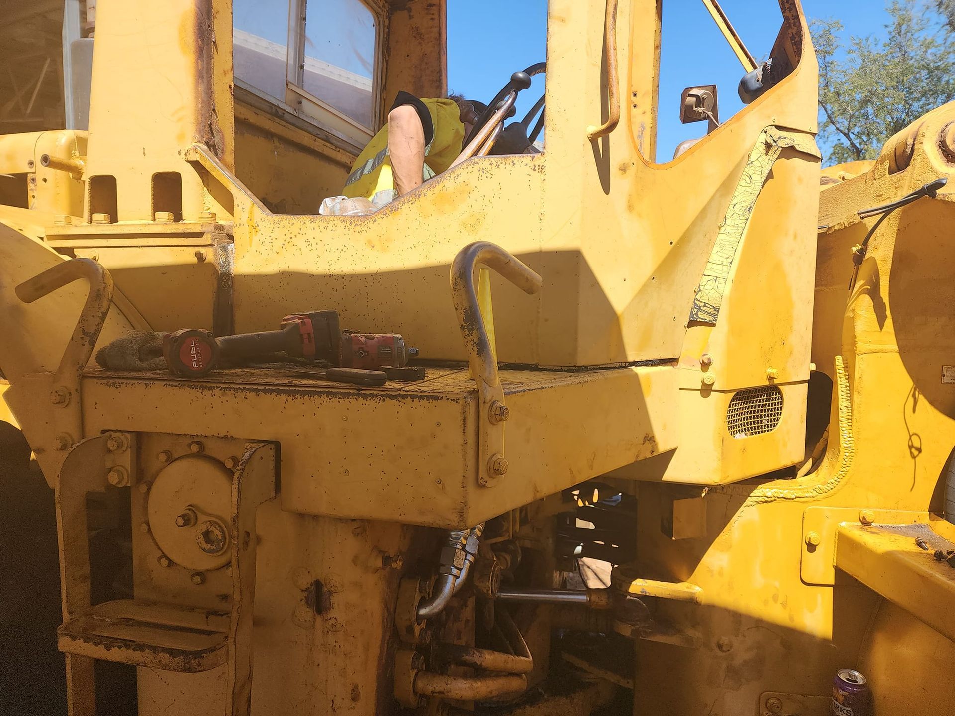 A Man Is Sitting In The Driver's Seat Of A Yellow Tractor — Rowdraulics NQ Pty Ltd in Mount Isa, QLD