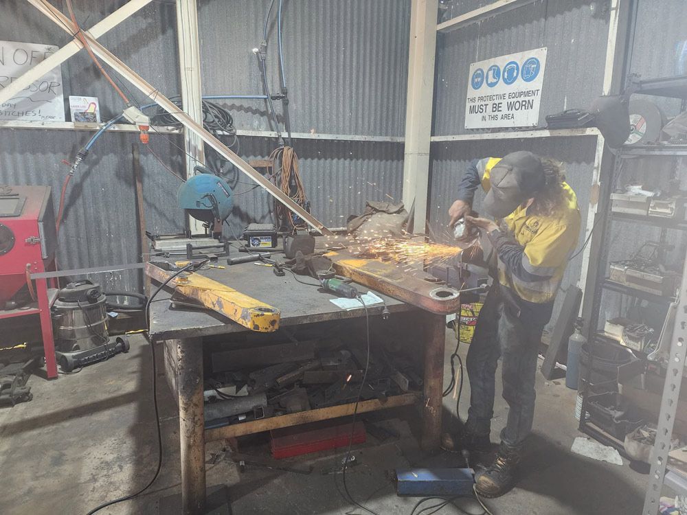 Two Men Are Working on a Piece of Metal in a Garage — Rowdraulics NQ Pty Ltd in Mount Louisa, QLD