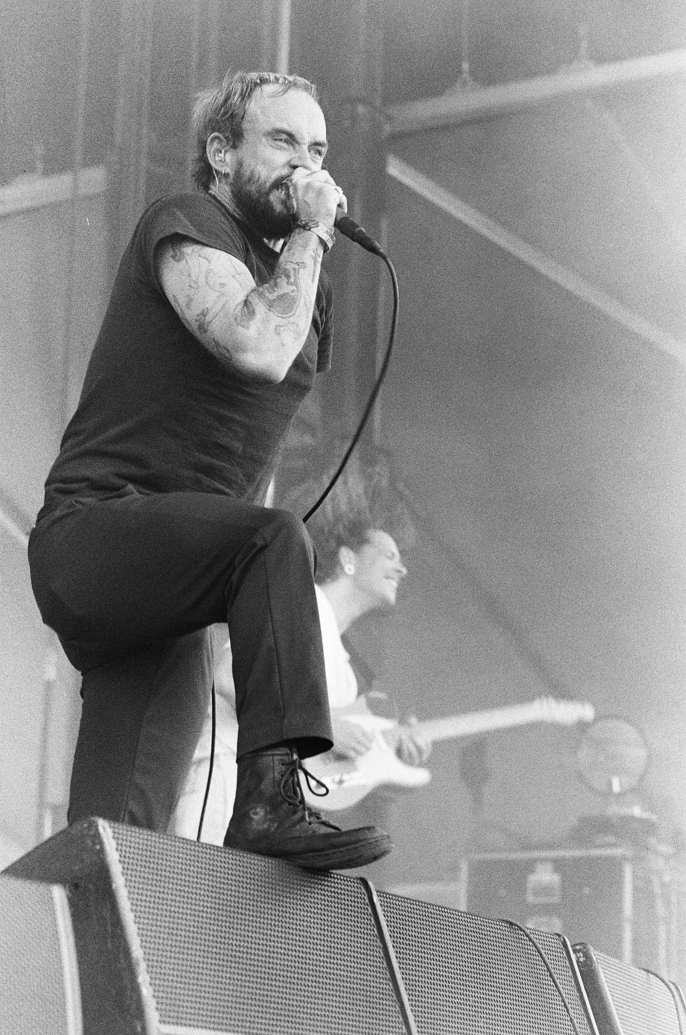 A man is singing into a microphone while sitting on a chair.