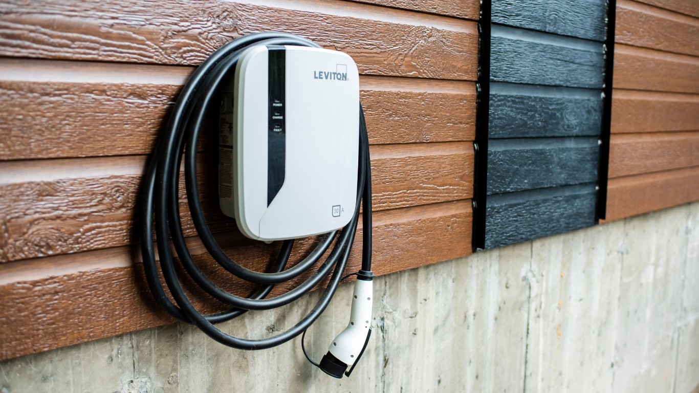 An electric car charger is attached to the side of a building.