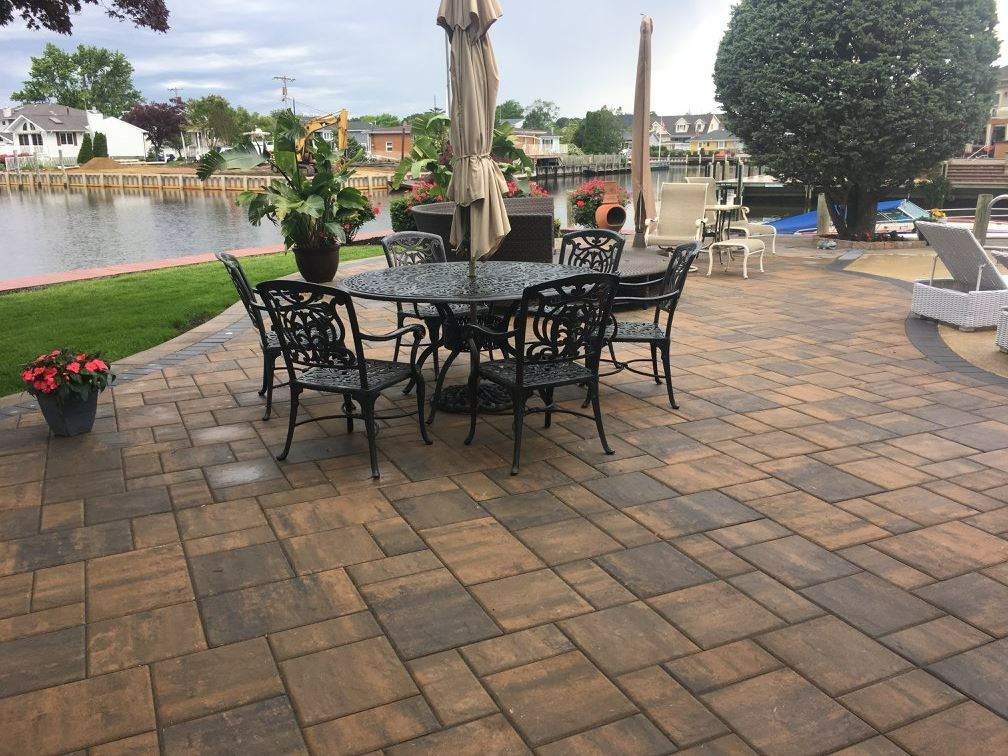 Patio with dark metal table and chairs, overlooking a waterway.