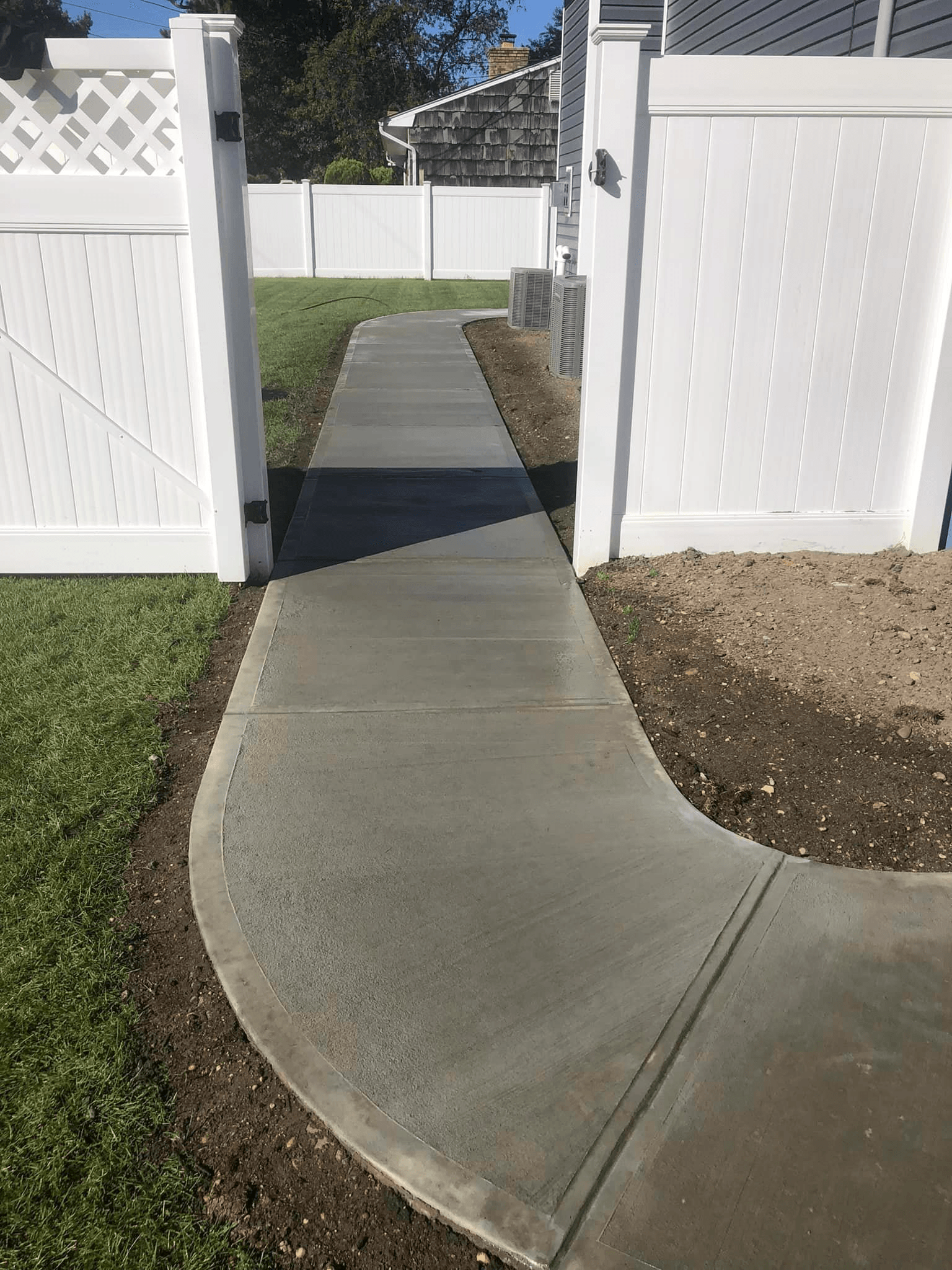 Concrete pathway through white fenced yard.