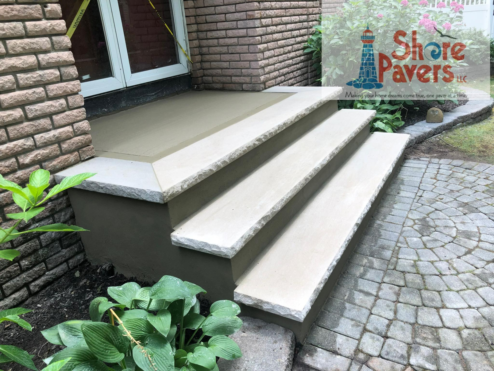 Concrete steps leading to a house with a brick facade, light gray with lighter steps.