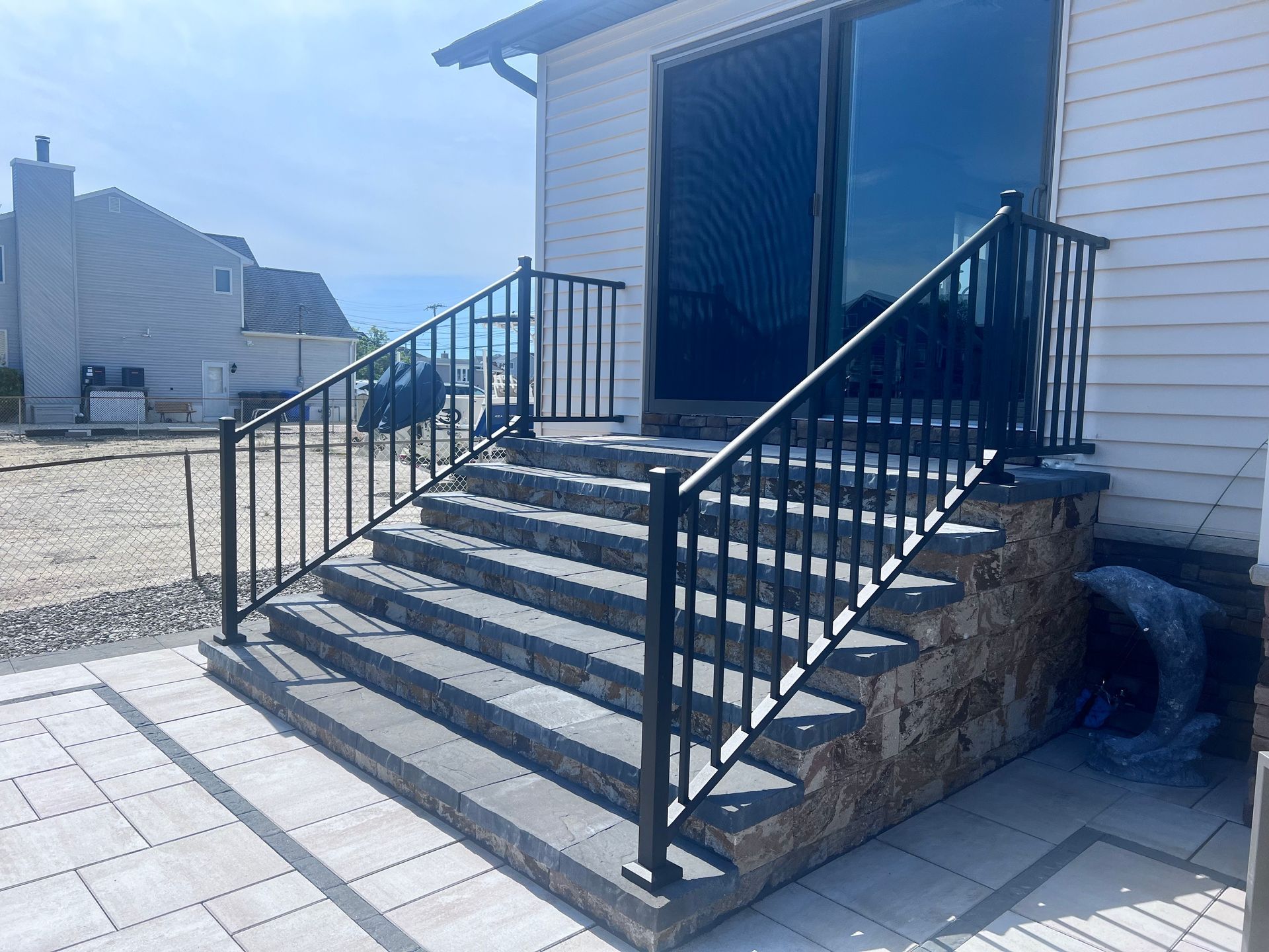 Stone steps with black railing leading to a house with a sliding glass door.