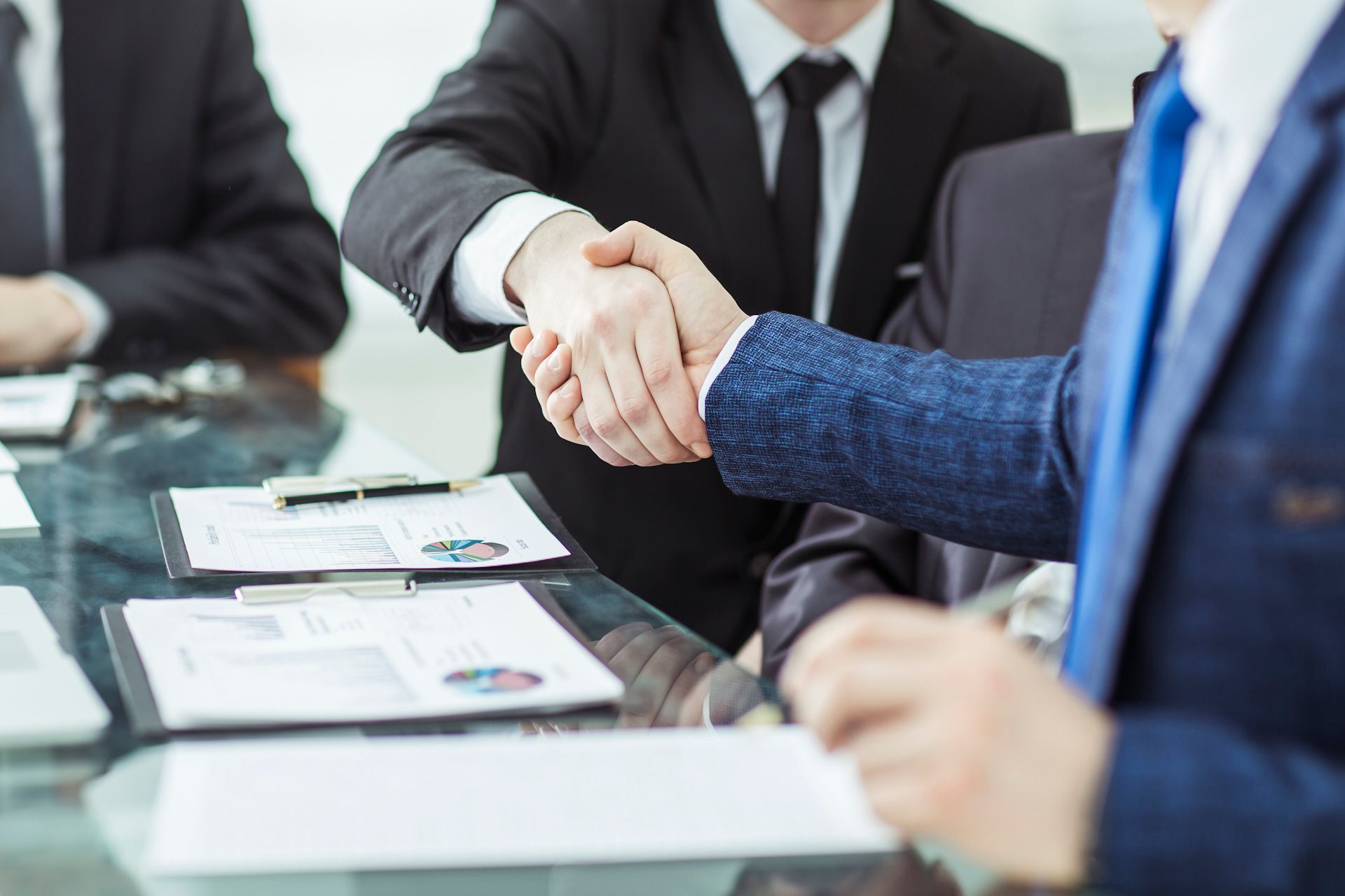 A group of business people are shaking hands over a table.
