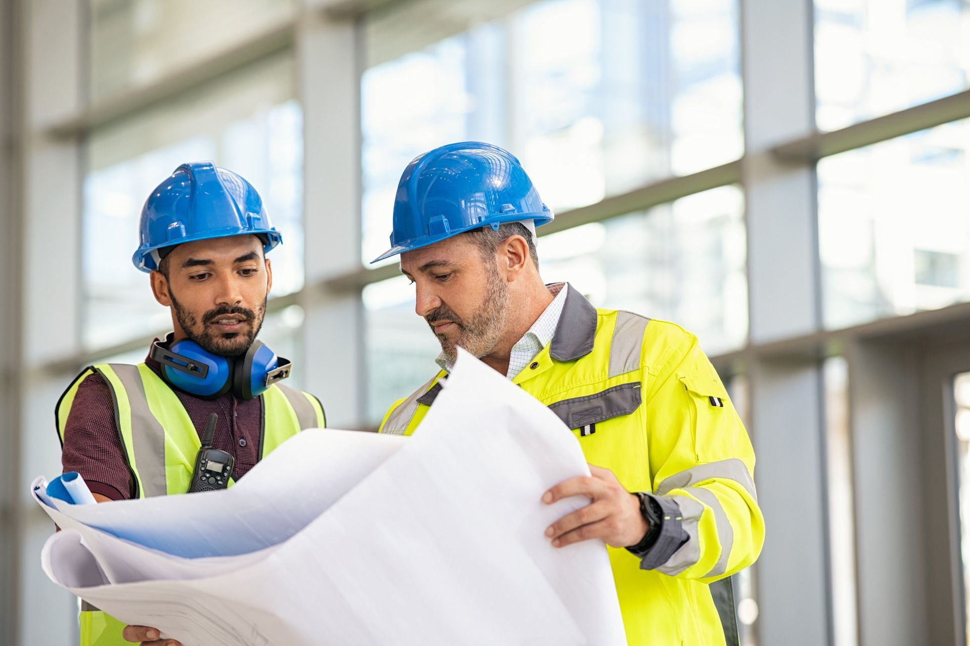 Two construction workers are looking at a blueprint together.