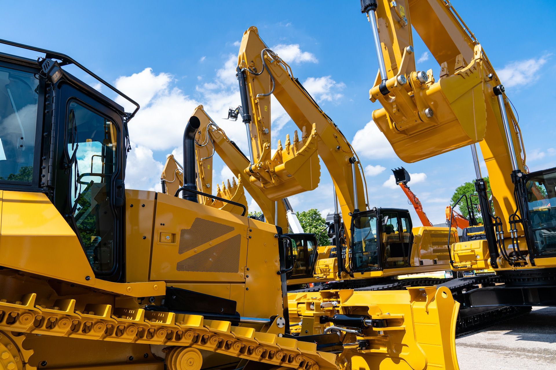 A group of yellow construction vehicles are parked in a lot.