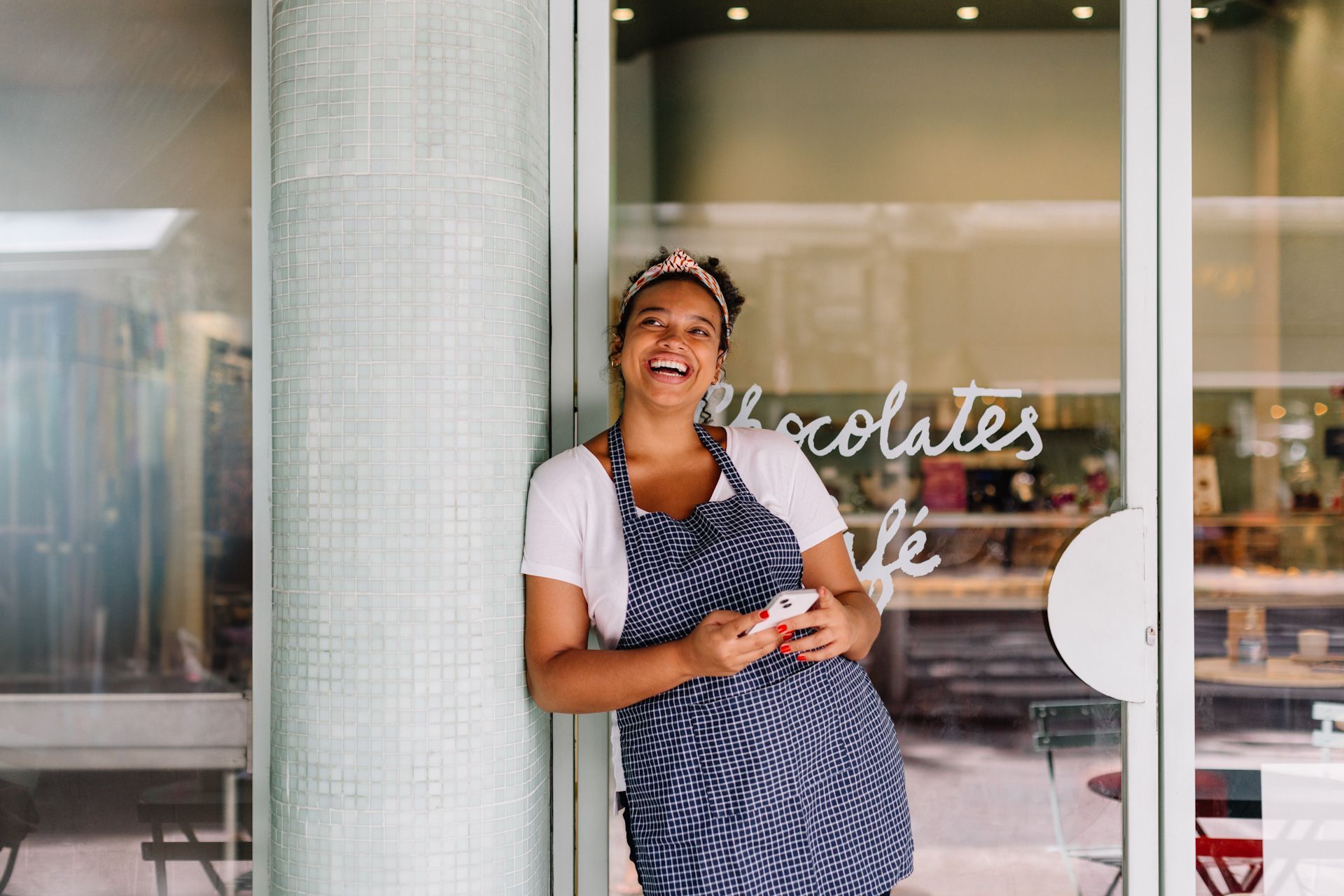 A woman is standing in front of a glass door holding a cell phone.