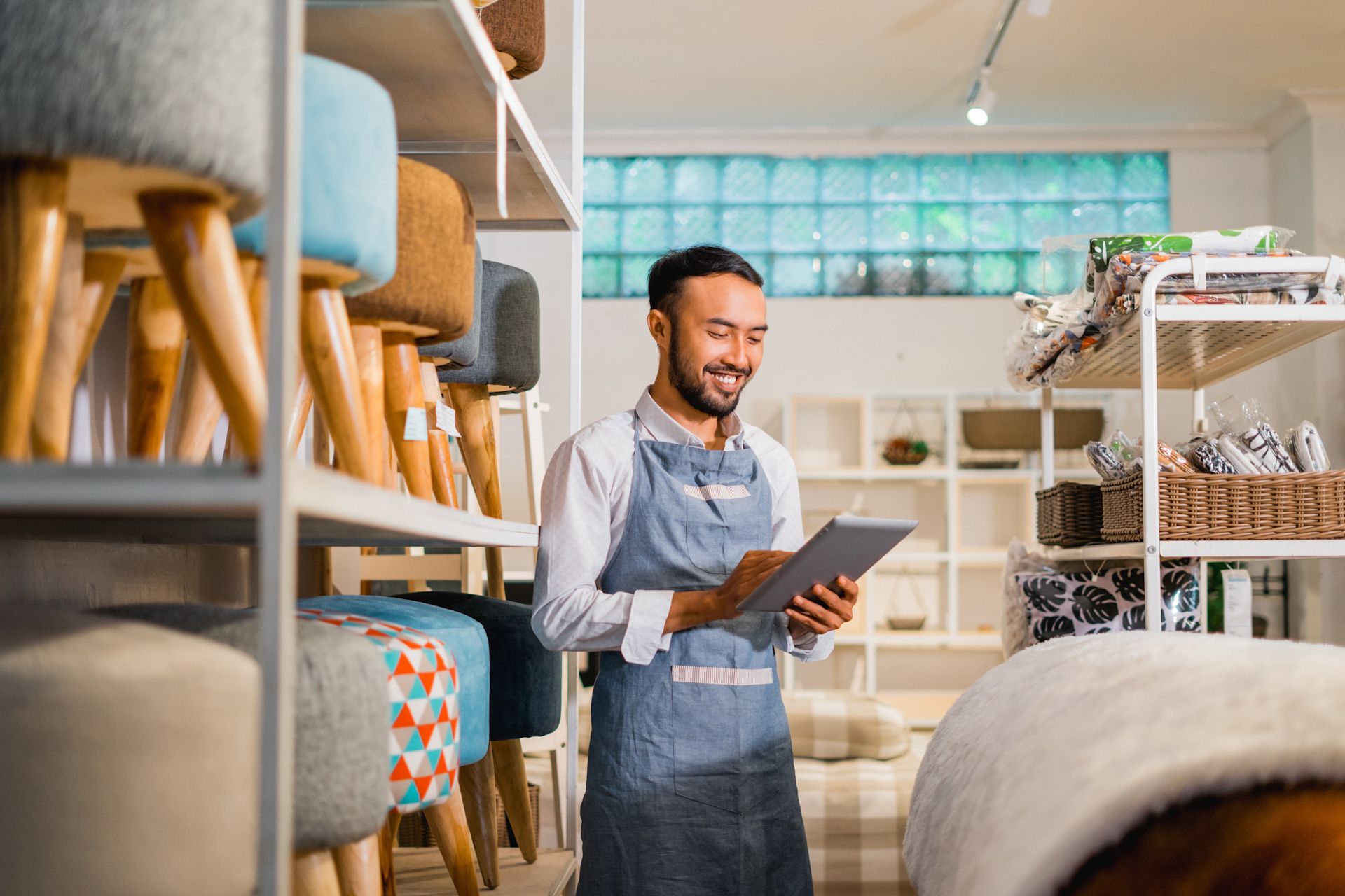 A man is using a tablet in a furniture store.