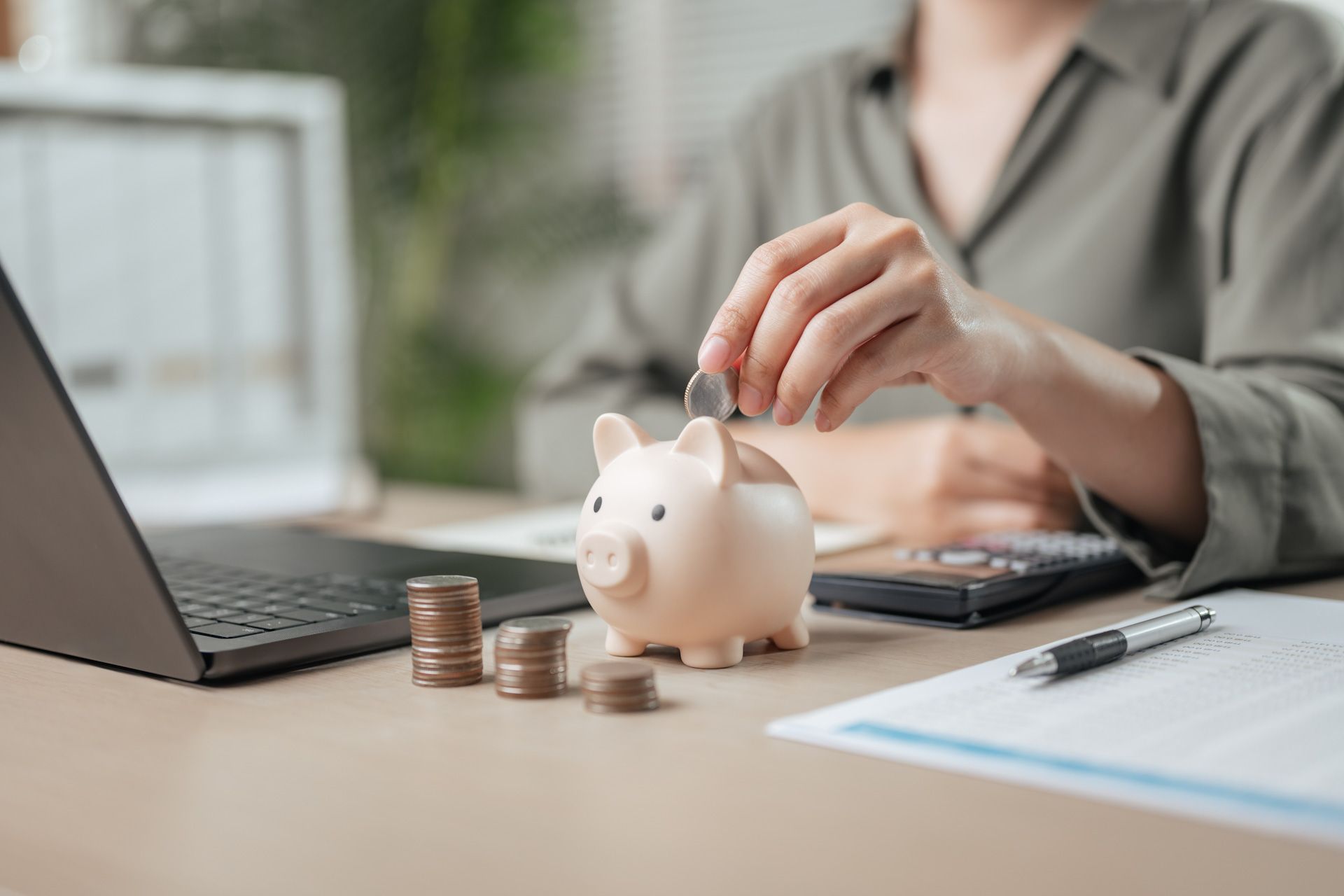 A woman is putting a coin into a piggy bank.