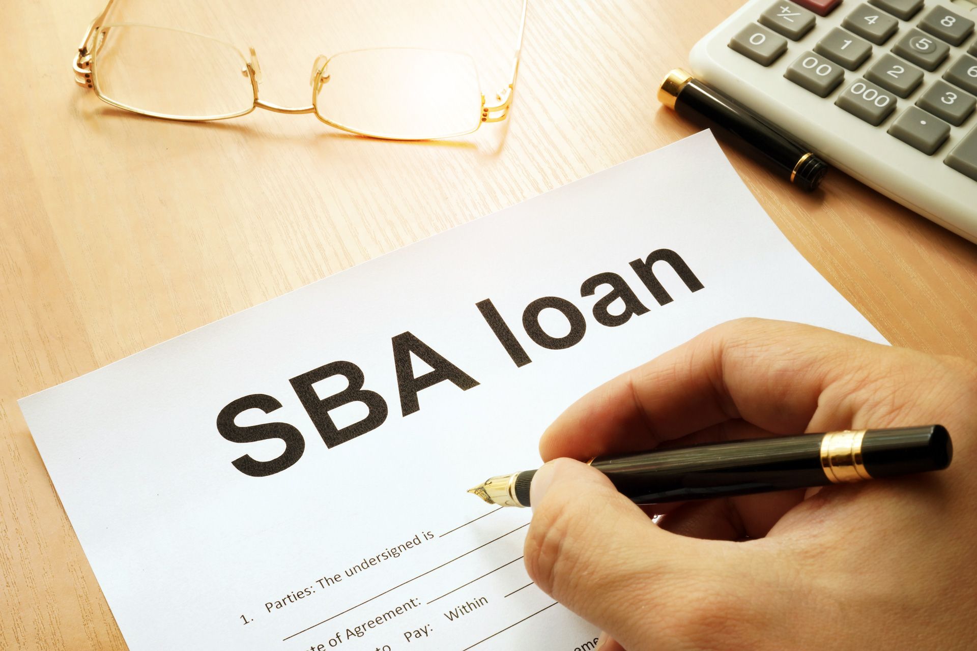 A person is signing a sba loan form with a pen