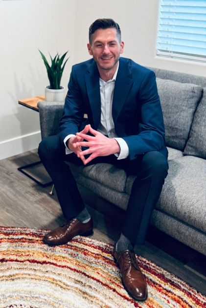 A man in a suit is sitting on a couch in a living room.