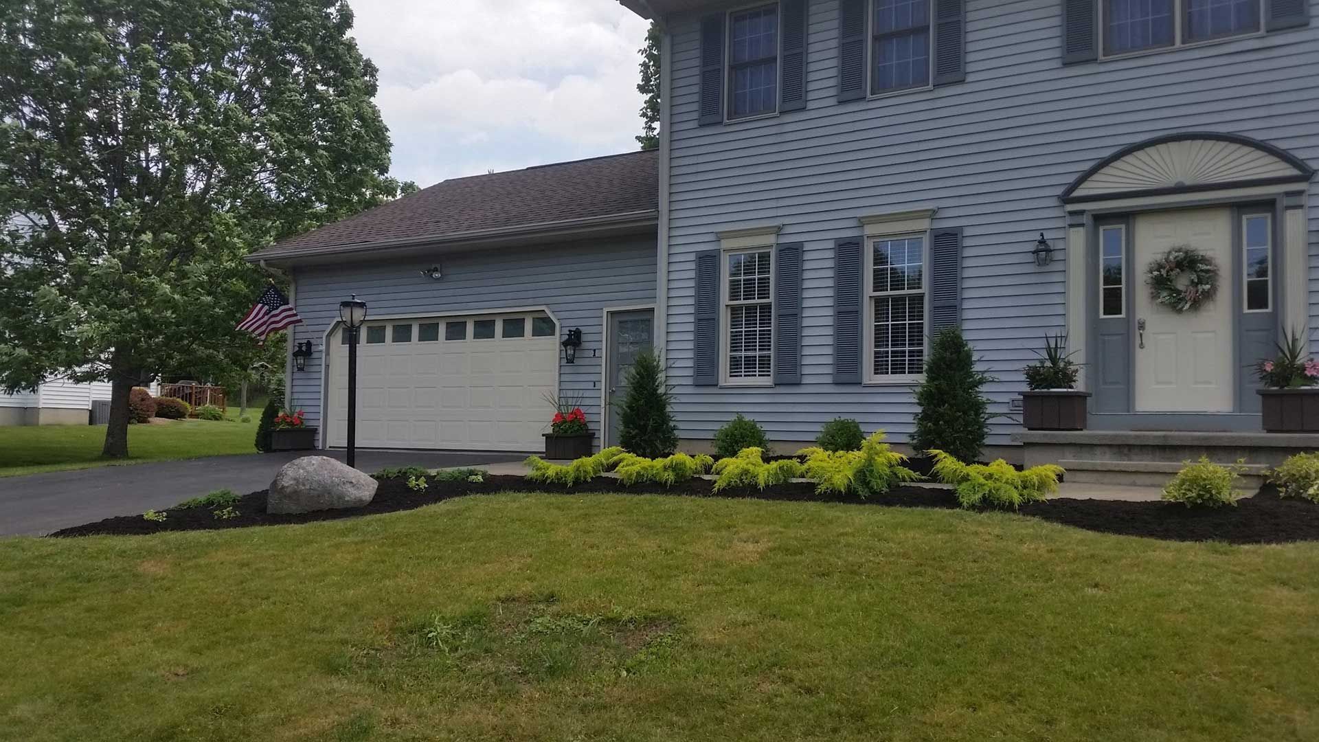 garage of blue house with flowerbed