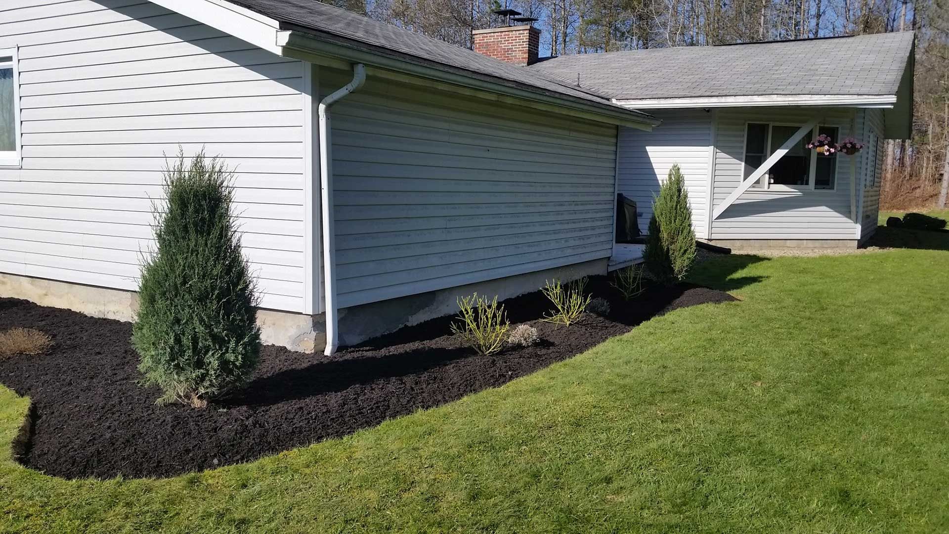 back of house with fresh black mulch and shrubs