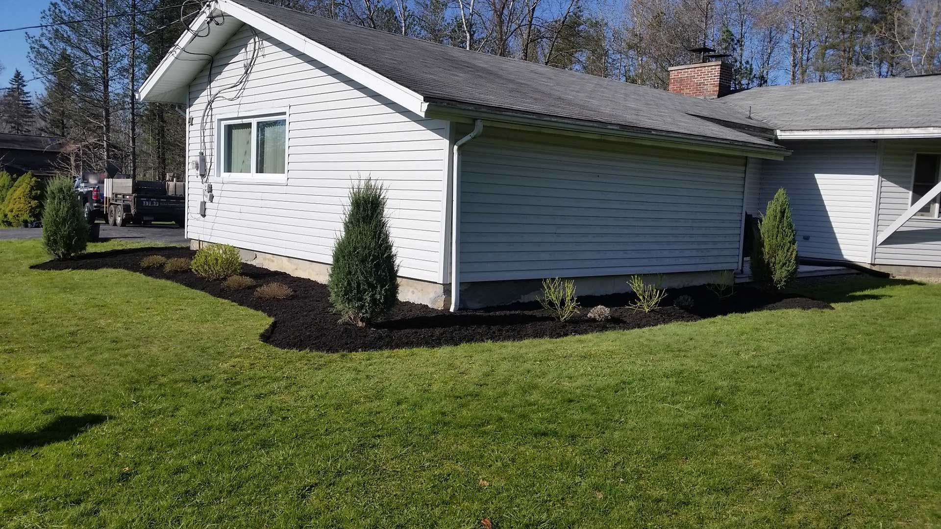 back of house with fresh black mulch and shrubs