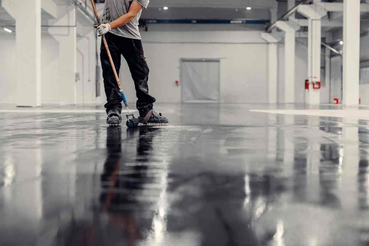Someone applying epoxy to concrete in a warehouse at Resilient Concrete Coatings near Cypress Texas (TX)