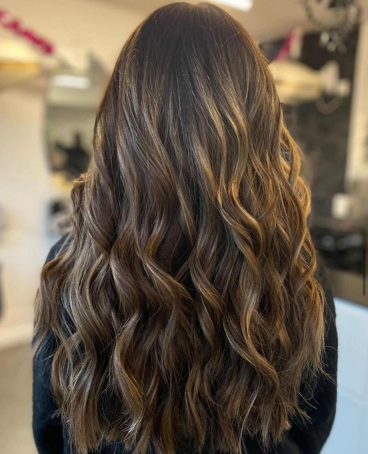 A woman with long brown hair has had a professional hair cut at a salon