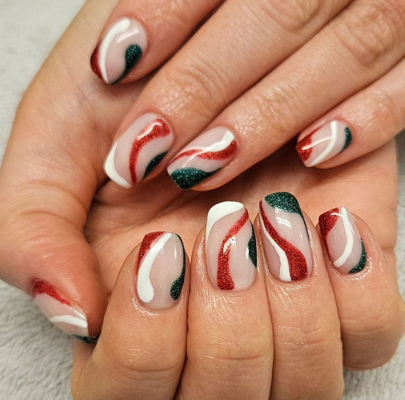 A woman's nails are painted red white and green at a beauty salon