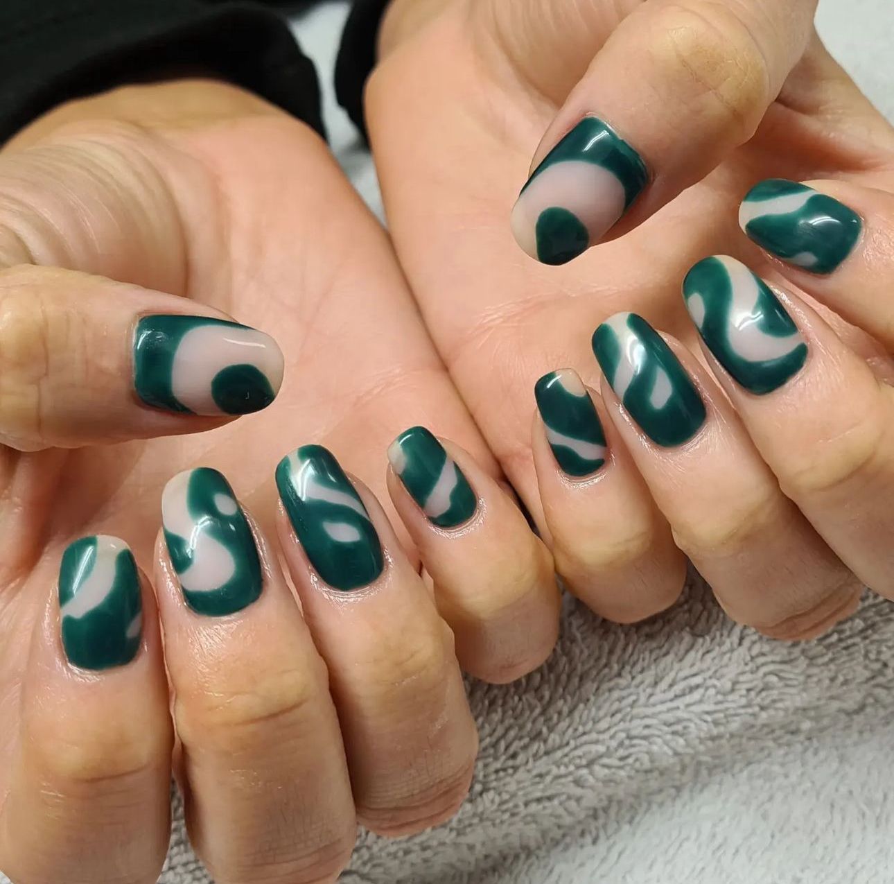 A close up of a woman 's hands with green nails done by a nail artist a a beauty salon in toddington and dunstable