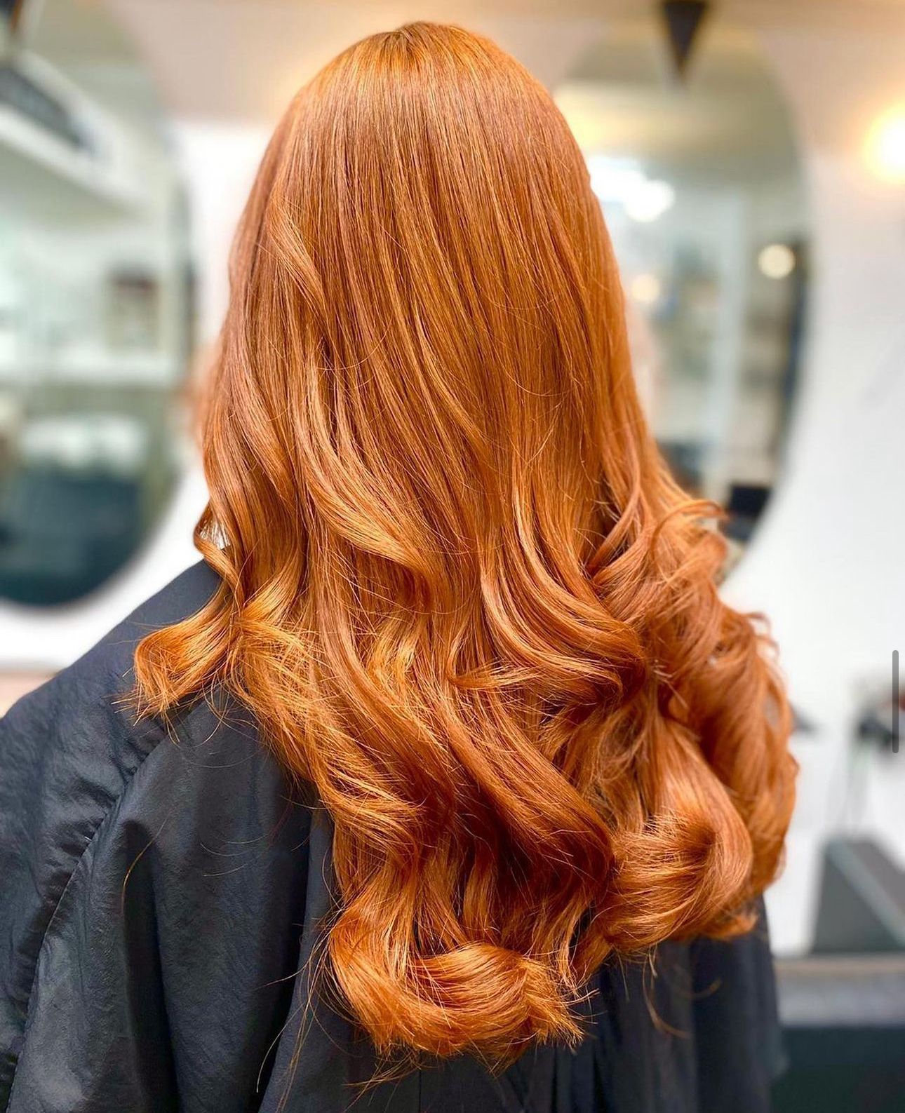 A woman with freshly cut long red hair is sitting in a chair in panache hair and beauty salon.