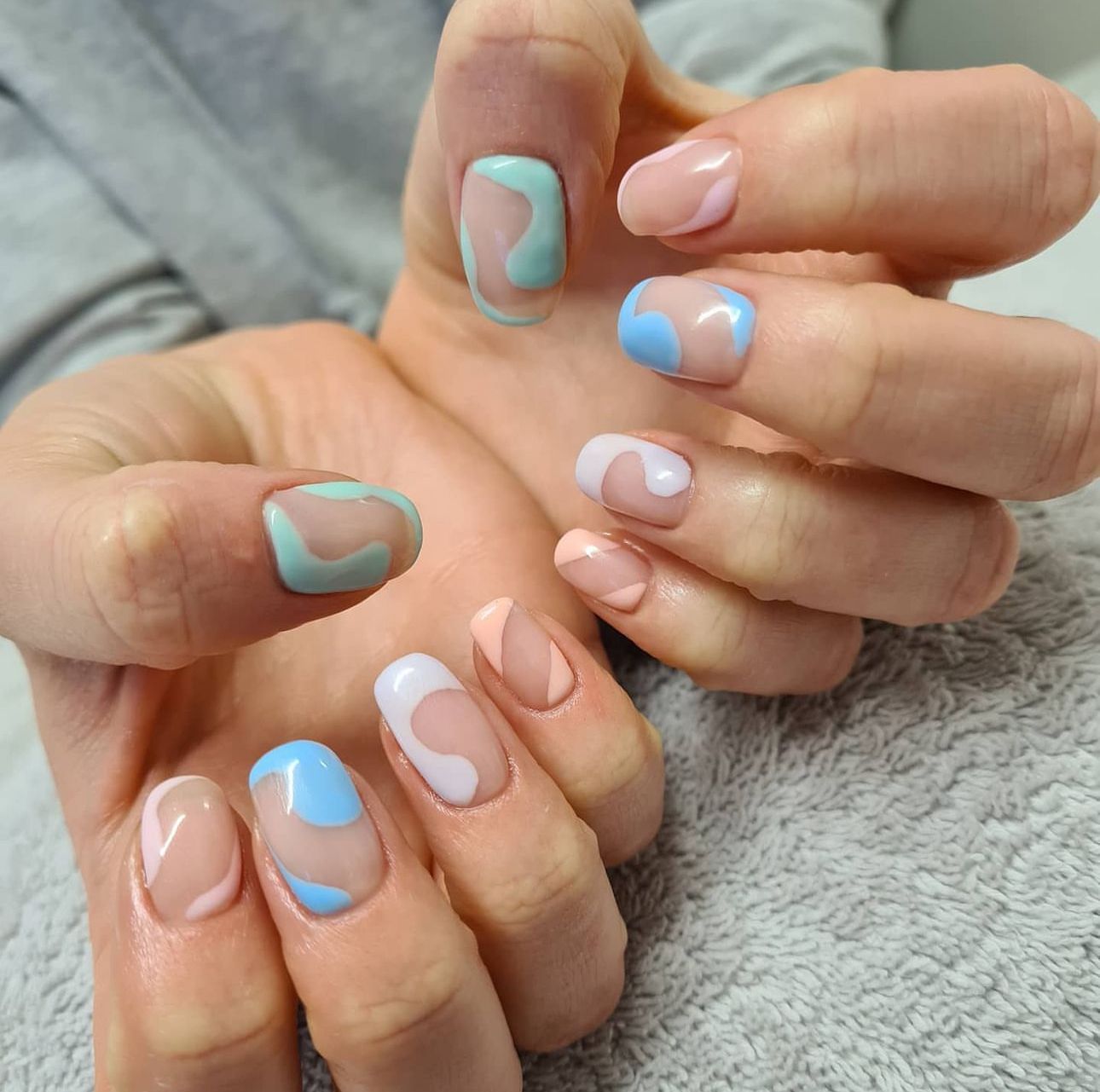 A close up of a person 's nails with a blue and pink design done by a nail artist at Panache hair and beauty salon