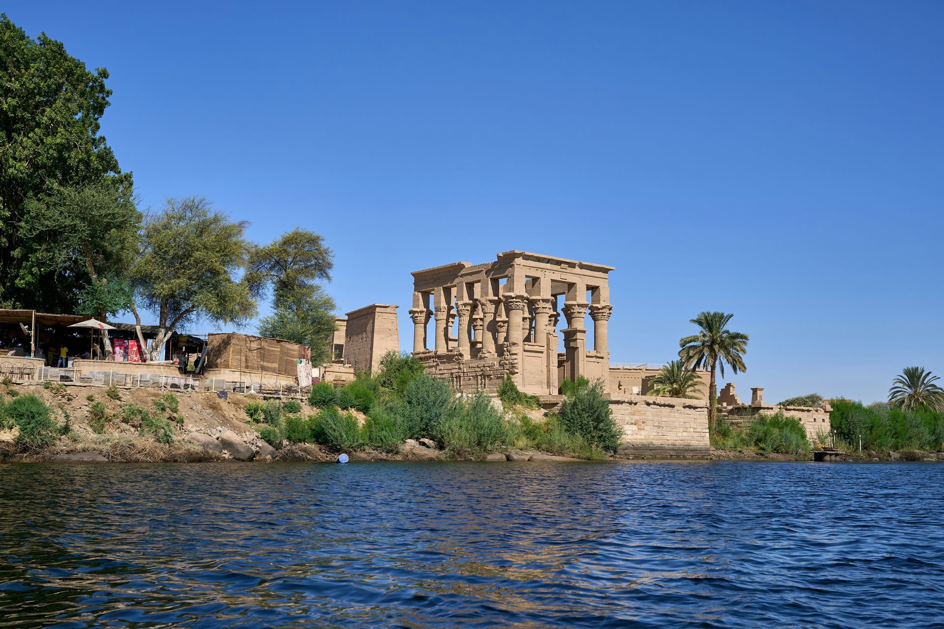 A premium Nile cruise perspective approaching the historic Philae Temple complex near Aswan