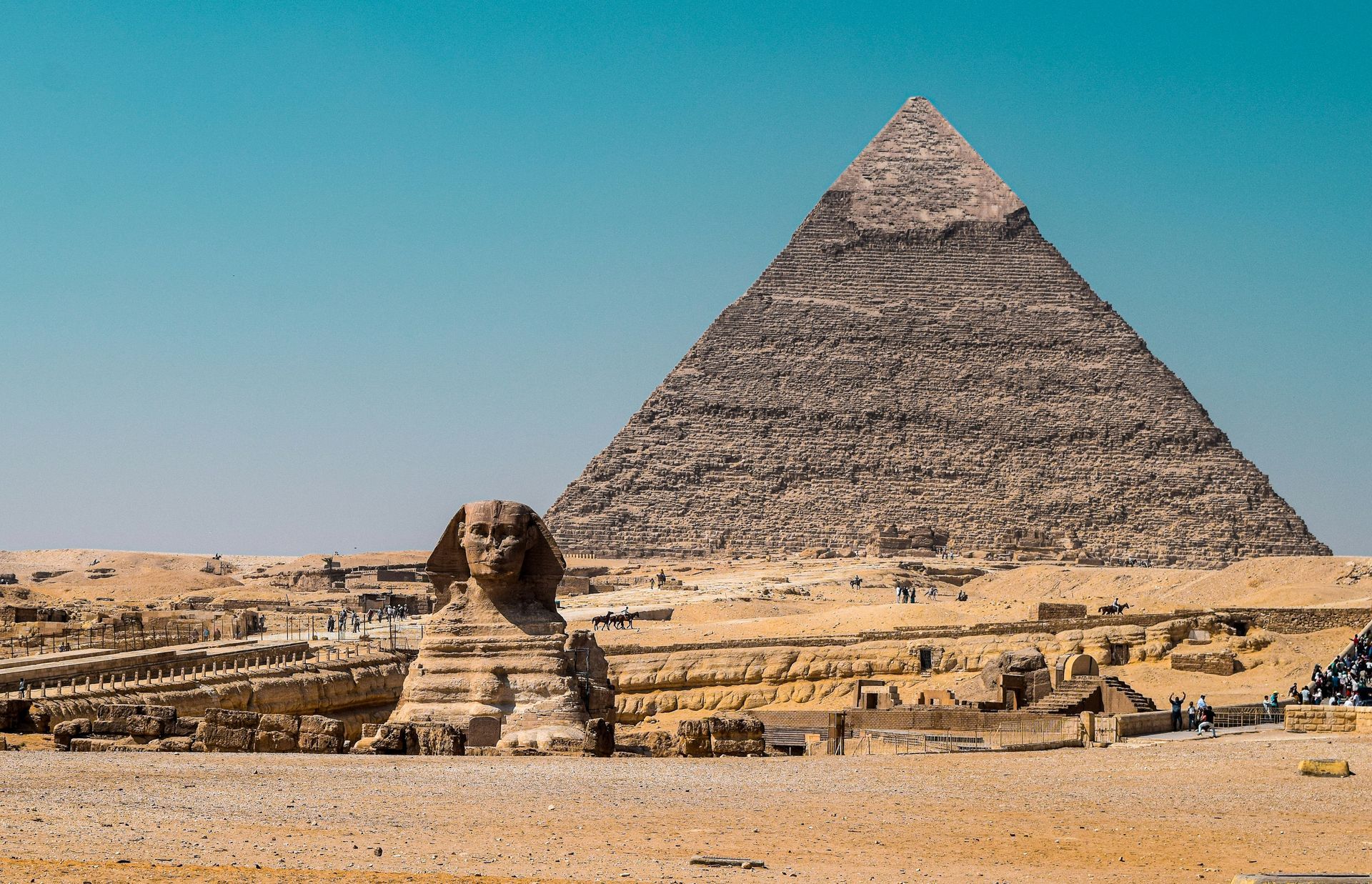 Wide landscape shot of the iconic Great Sphinx of Giza with a pyramid rising behind it