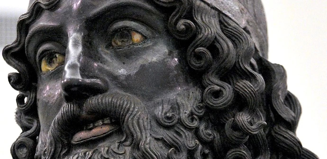 Lastre di vetro verticali di diverse altezze sono disposte in fila sotto un soffitto di lamiera ondulata.